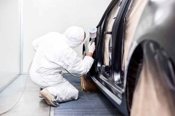 worker painting a car in a special painting box